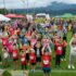 Eine Gruppe von Menschen (größtenteils Kinder) steht auf einem Sportplatz und formt mit den Händen ein Herz © C&D Moser, Foto Moser